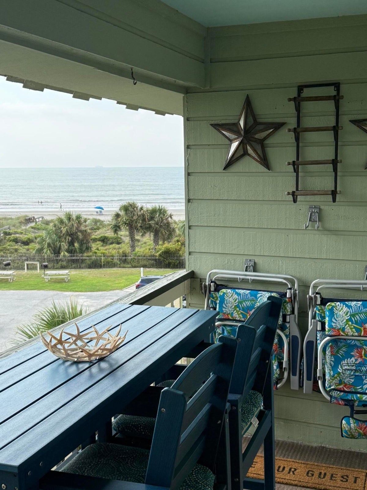 A covered outdoor seating area with a view of the ocean, a star decoration, and a ladder on the wall.
