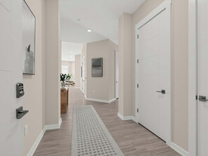 Un couloir moderne avec un plancher en bois, un tapis à motifs et une porte dotée d’un système de verrouillage à clavier.