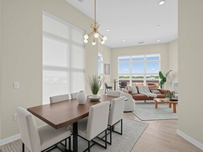 A modern interior with a dining area, a living room, and large windows.
