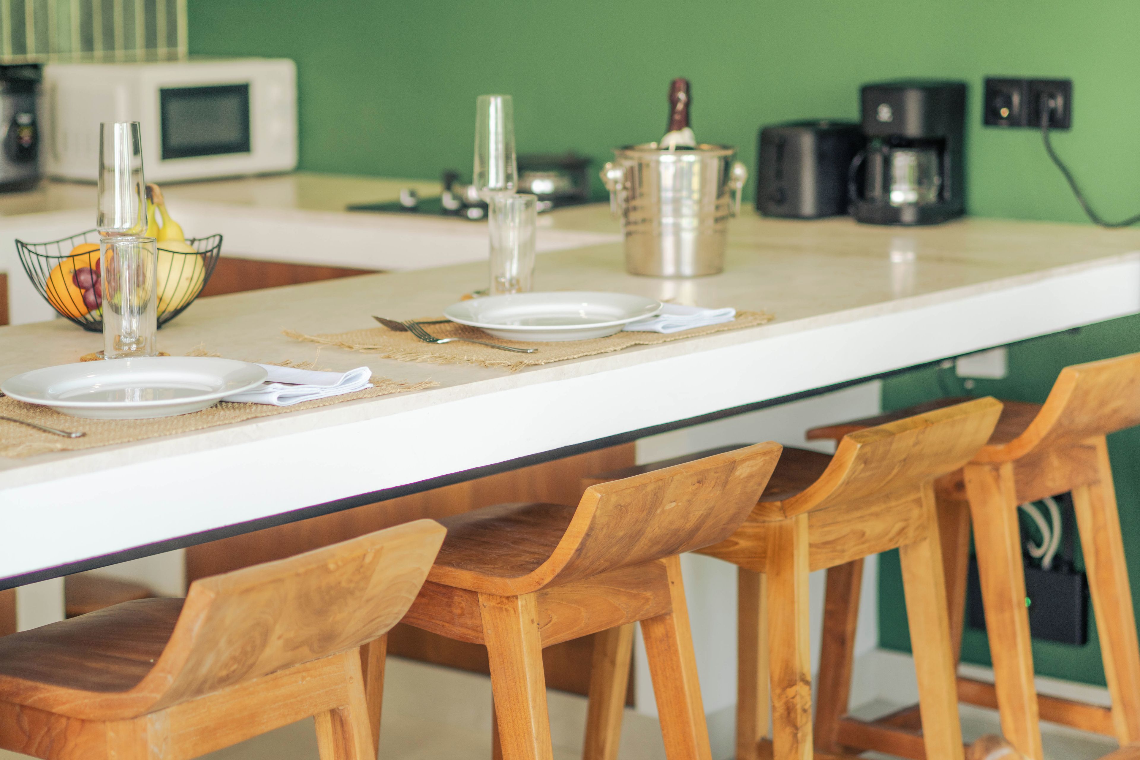 A kitchen counter with a white surface, a fruit bowl, a coffee maker, and a kettle.