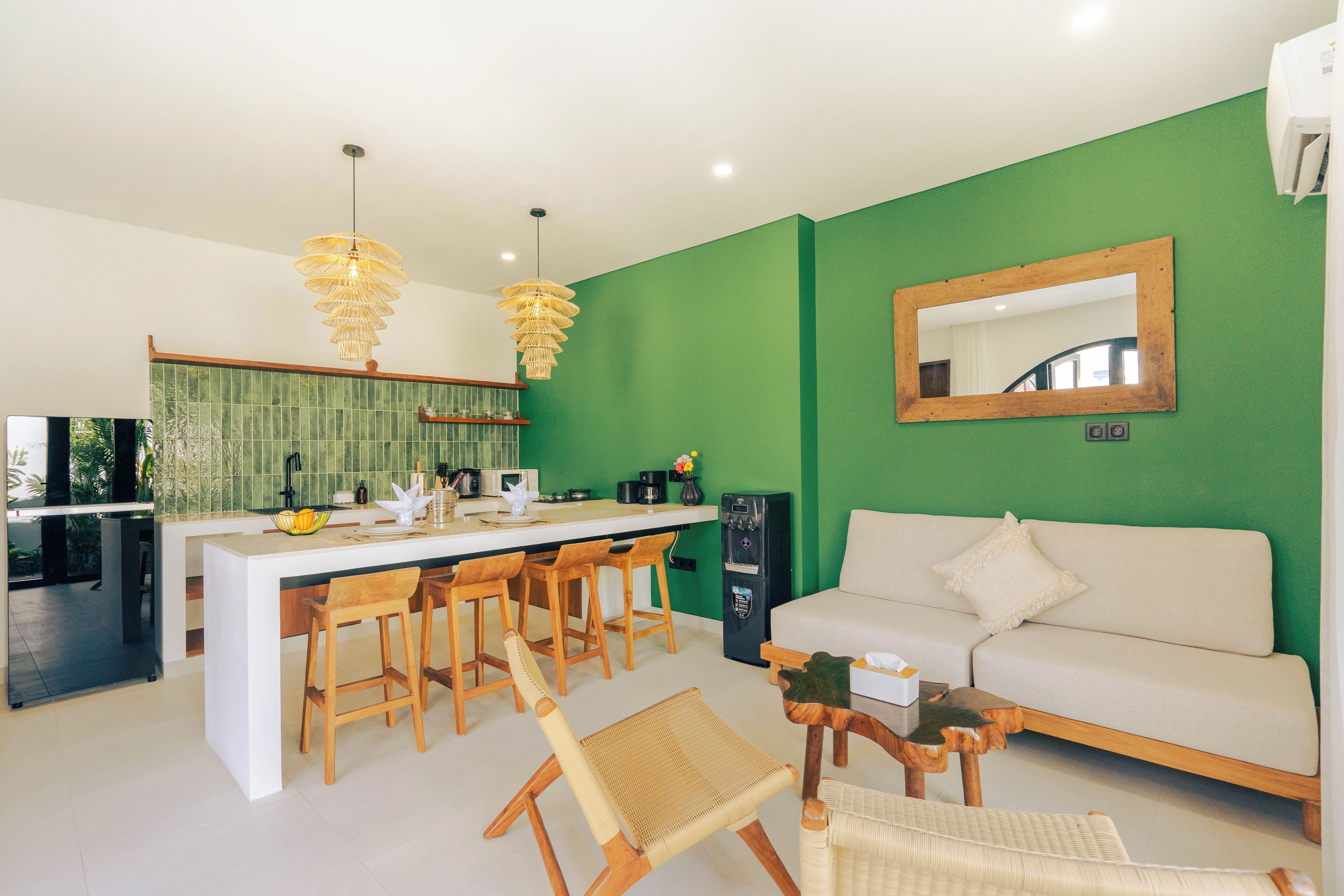 Cozinha moderna com ilha central, banquetas, sofá e um espelho grande.