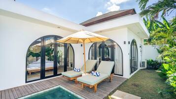 Uma casa moderna com piscina, duas espreguiçadeiras e um grande guarda-sol.