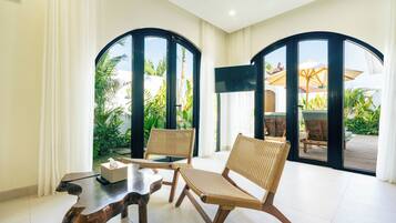 Una habitación con dos sillones de mimbre, una mesa de madera y un ventanal con vistas a un jardín.
