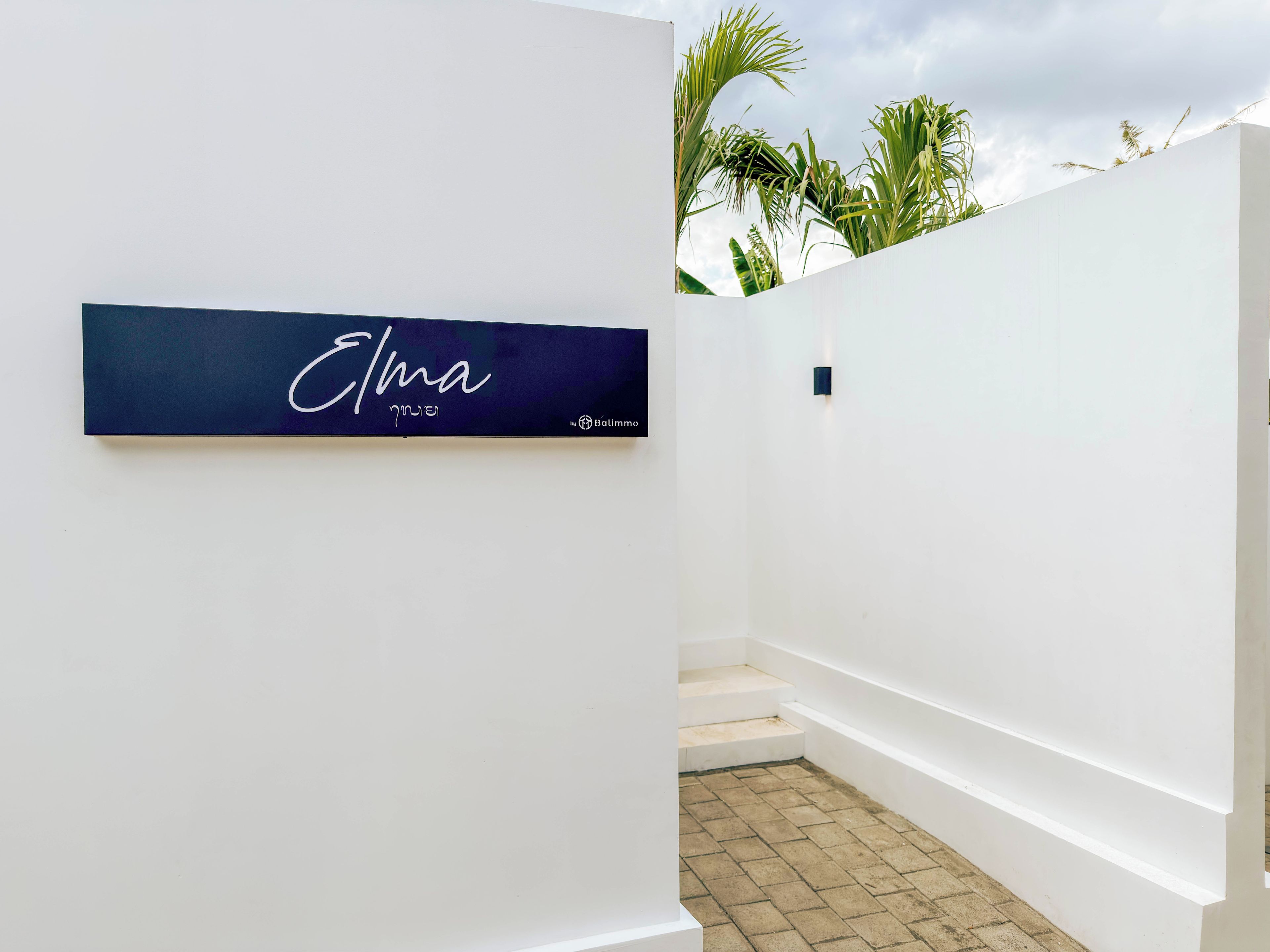 Un intérieur moderne avec un mur blanc et une enseigne bleu foncé portant le nom « Elma » et un logo.