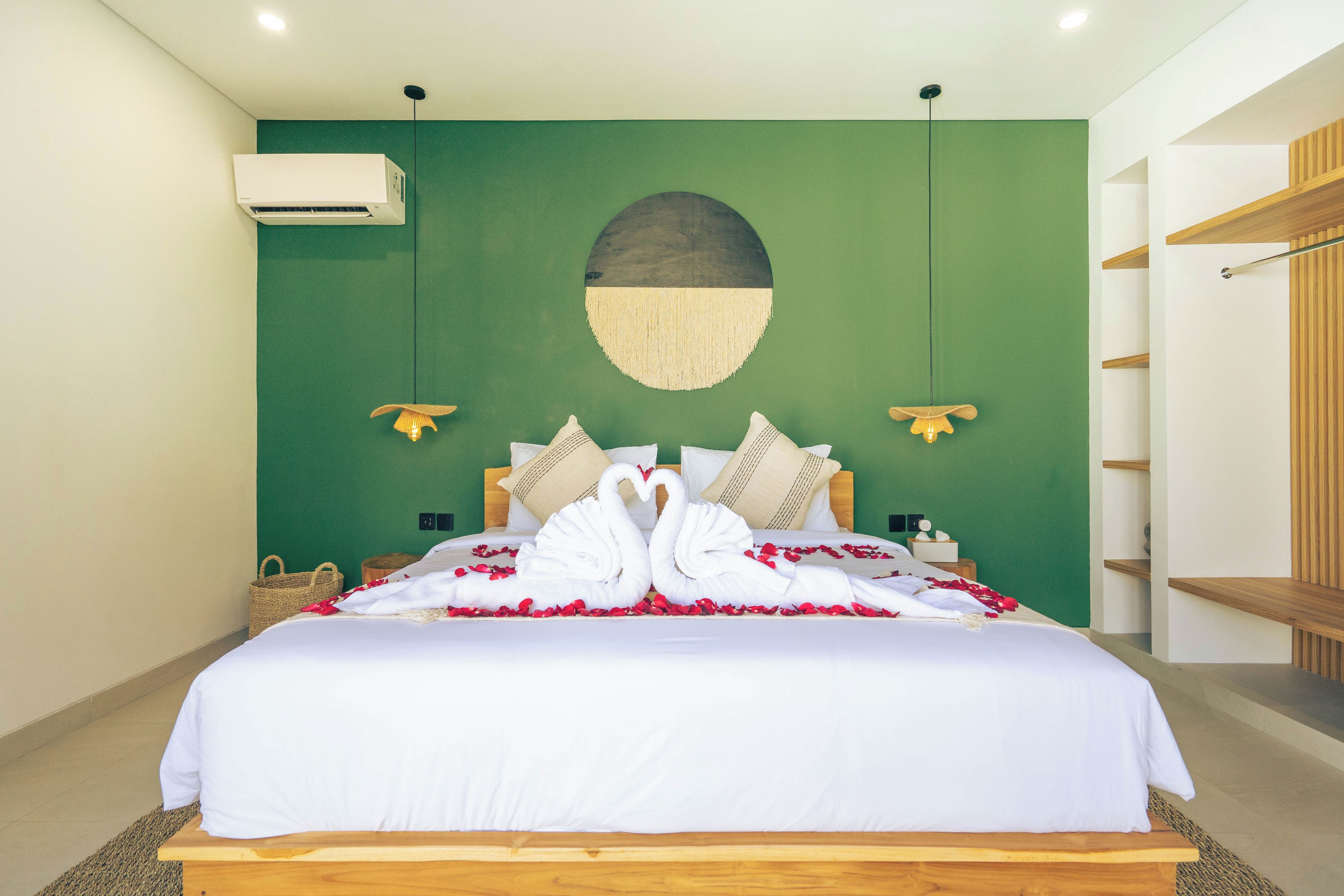 Quarto de hotel com cama, ar condicionado fixado na parede, um objeto decorativo na parede e um armário de prateleiras de madeira.
