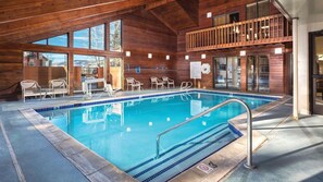 Una piscina interior con paredes de madera y un balcón con vistas a la piscina.