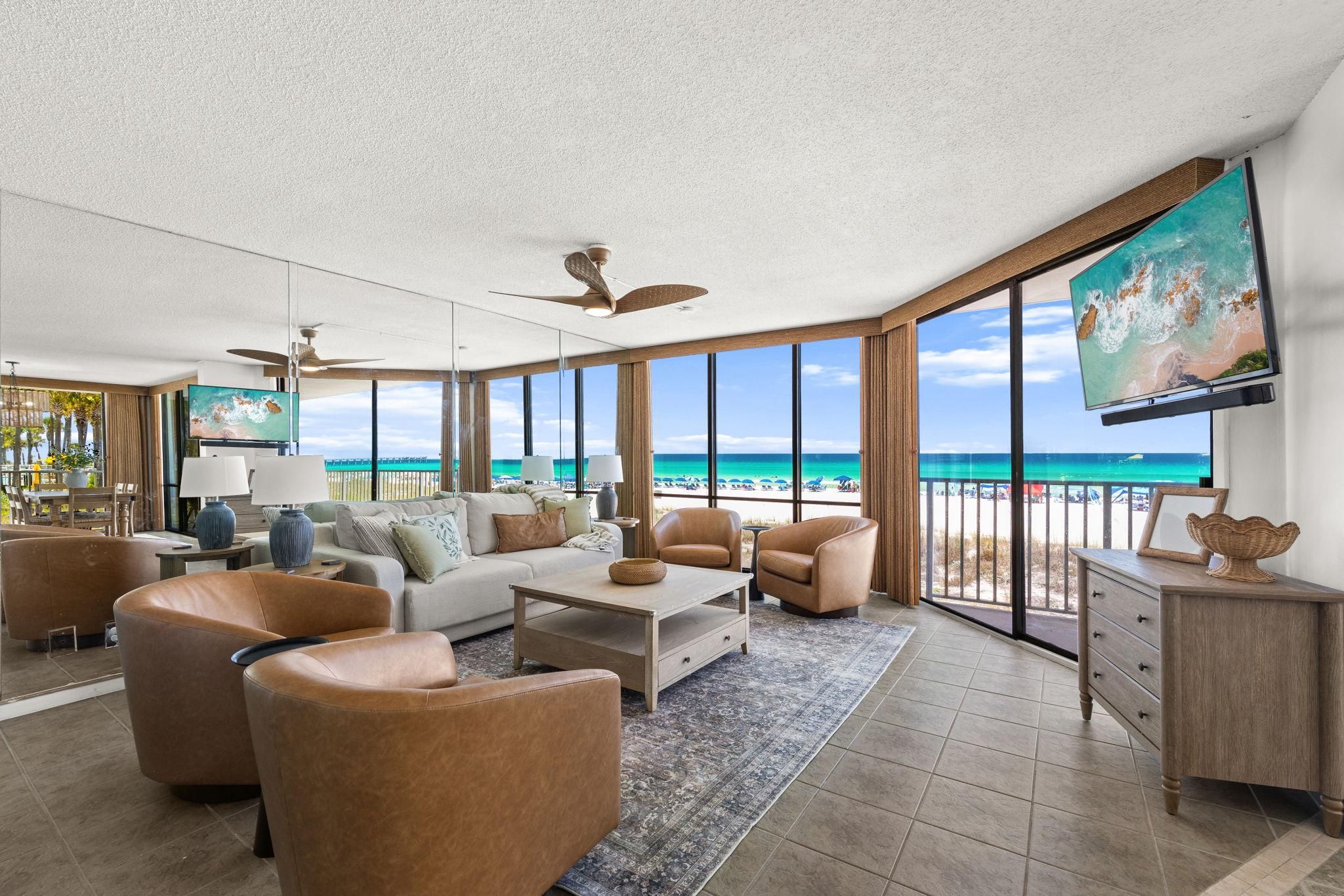 Un salón espacioso con televisor grande, asientos cómodos y vista a la playa.
