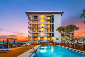 A hotel with a swimming pool, multiple balconies, and a view of the ocean at sunset. - Windward 108 (Panama City Beach)