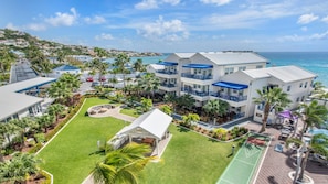 A resort with multiple-story buildings, a pool area, and a view of the ocean.