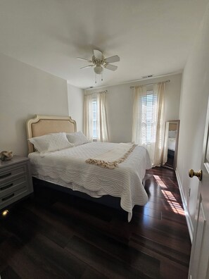 Ein Schlafzimmer mit einem Bett, einem Nachttisch, einem Deckenventilator und einer Tür mit Messinggriffen.