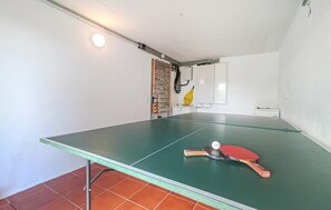 A ping pong table in a room with a white wall, a small white cabinet, and a yellow object on the wall. - Beautiful home in Kemmenau with house a panoramic view (Kemmenau)