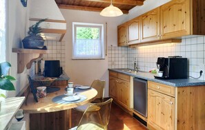 A kitchen with wooden cabinets, a dining table with chairs, a coffee maker, and a window. - Beautiful home in Kemmenau with house a panoramic view (Kemmenau)