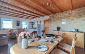 A dining area with a wooden table set for four, surrounded by chairs, a vase of flowers, and a stone wall. - Beautiful home in Kemmenau with house a panoramic view (Kemmenau)