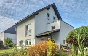 A two-story house with a sloped roof, a satellite dish, and a small garden with various plants. - Beautiful home in Kemmenau with house a panoramic view (Kemmenau)
