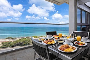 A balcony with a table set for breakfast overlooking a beach and ocean. - Azure Oceanfront Luxury I Eagle Beach View I 3 BR (Oranjestad)