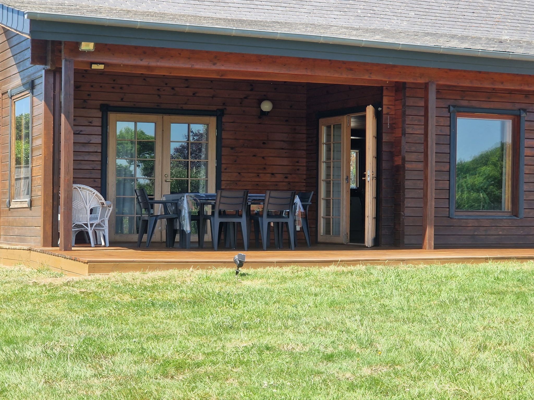 Une cabane en bois avec un porche couvert, une table avec des chaises et une pelouse devant.