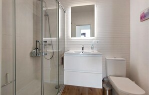 A modern bathroom with a glass-enclosed shower, a white sink with a mirror above, and a toilet. - Apartamento Benalmadena vistas (Benalmadena)