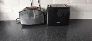 Eine Küche mit einem Toaster und einer Brotdose auf einer schwarzen Arbeitsplatte.