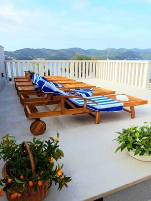 A terrace with wooden lounge chairs and a view of the sea and hills. - Villa Oaza Ora | Private pool & Beach nearby, Pelješac (Kučište)