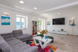 A modern living room with a grey sofa, a white coffee table, and a colorful rug. - Villa Oaza Ora | Private pool & Beach nearby, Pelješac (Kučište)