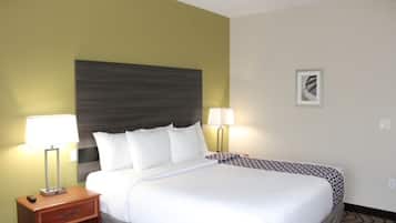 Una habitación de hotel con una cama, dos lámparas de noche, una mesita de noche y un cuadro en la pared.