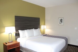 A hotel room with a bed, two bedside lamps, a nightstand, and a framed picture on the wall. - Ullah Lodging  (Corpus Christi)