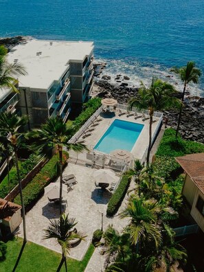 A resort with a swimming pool, palm trees, and a view of the ocean. - The Alani at Kona Shores (Kailua-Kona)