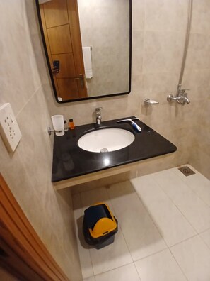 Ein Badezimmer mit schwarzem Waschbecken, Spiegel, Dusche und Toilette.