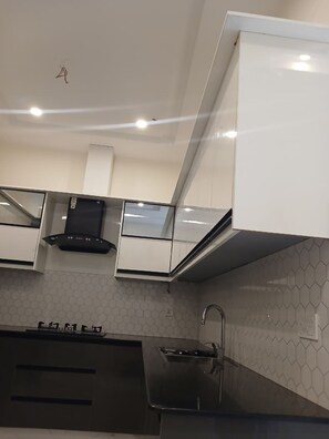 A modern kitchen with white cabinetry, a stainless steel sink, and a hexagonal tile backsplash.