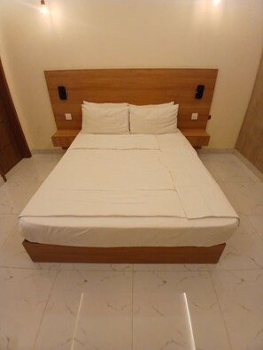 A neatly made bed with a wooden headboard, a bedside table, and a nightstand.