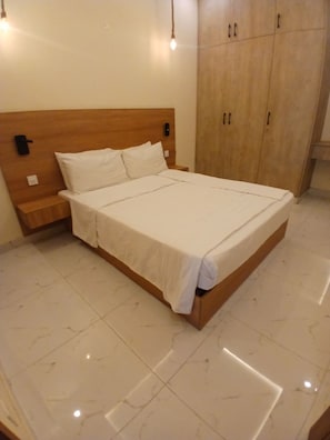 A bed with a wooden headboard, white bedding, and a nightstand. - Tranquil 1-bedroom apartment with AC in welcoming Lahore (Lahore)