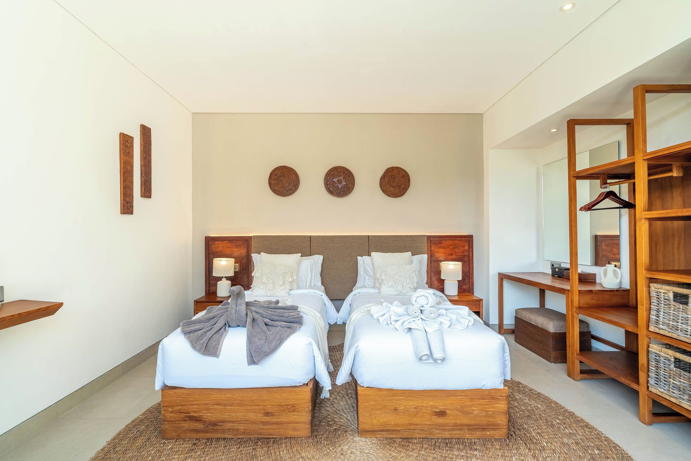 Habitación de hotel con cama doble, mesitas de noche, cabecero de madera, espejo, armario y estante en la pared.
