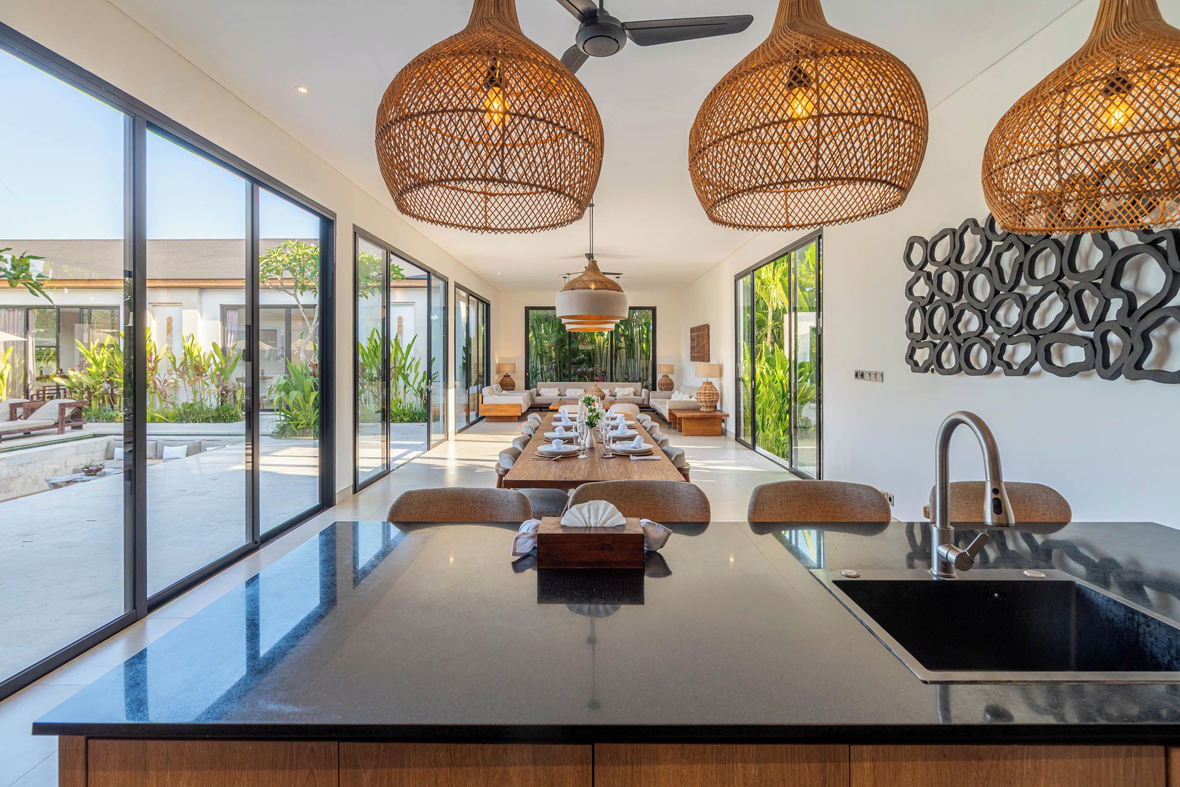 Una cocina moderna con una isla grande, luces colgantes y vistas al exterior.