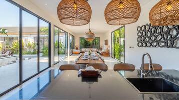 Una cocina moderna con una isla grande, luces colgantes y vistas al exterior.