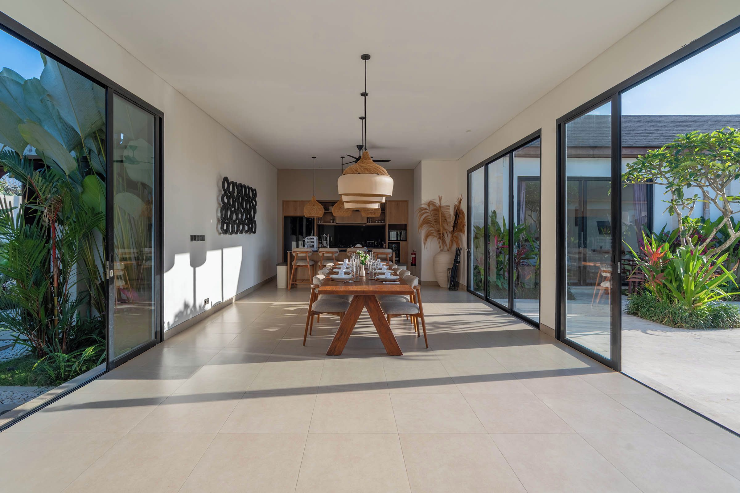 A modern interior with a dining area, large glass doors, and a view of the outdoors.