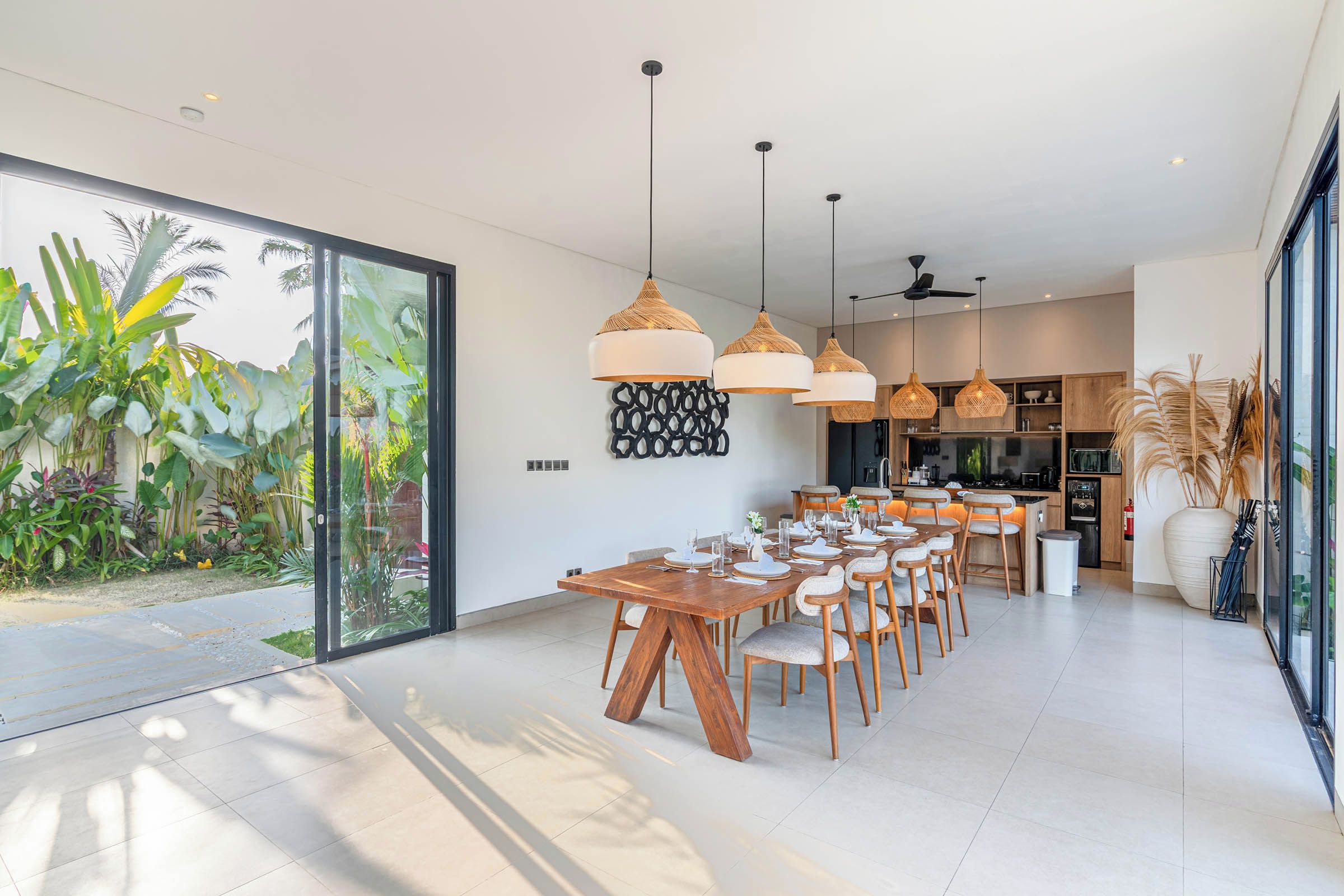 A modern dining area with a large table, multiple chairs, and pendant lighting.