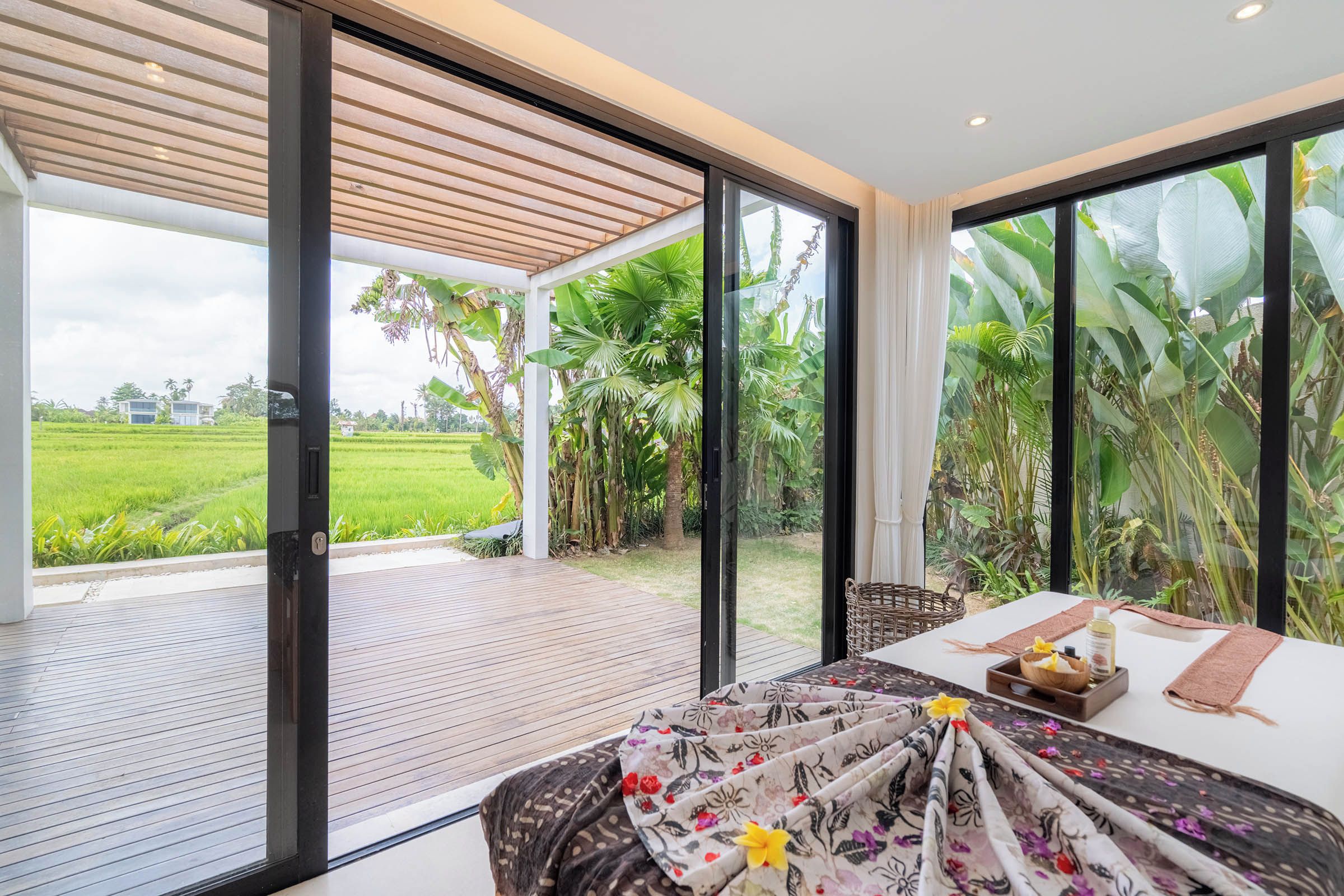 A modern room with a large sliding glass door leading to a covered outdoor area with a wooden deck.