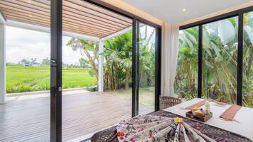 A modern room with a large sliding glass door leading to a covered outdoor area with a wooden deck.