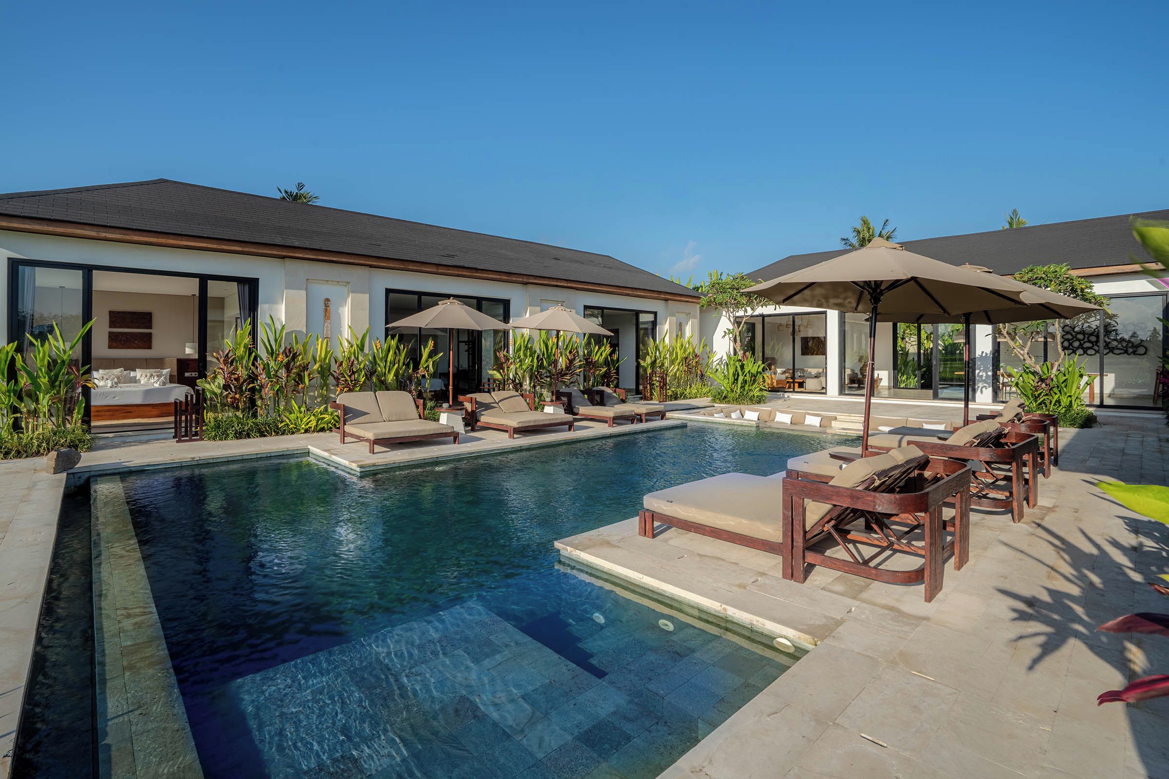 A modern house with a swimming pool, outdoor seating, and a well-maintained garden.