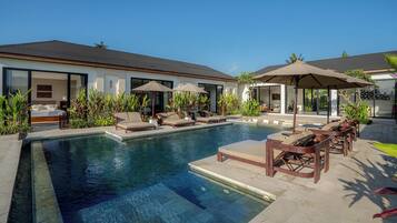 A modern house with a swimming pool, outdoor seating, and a well-maintained garden.