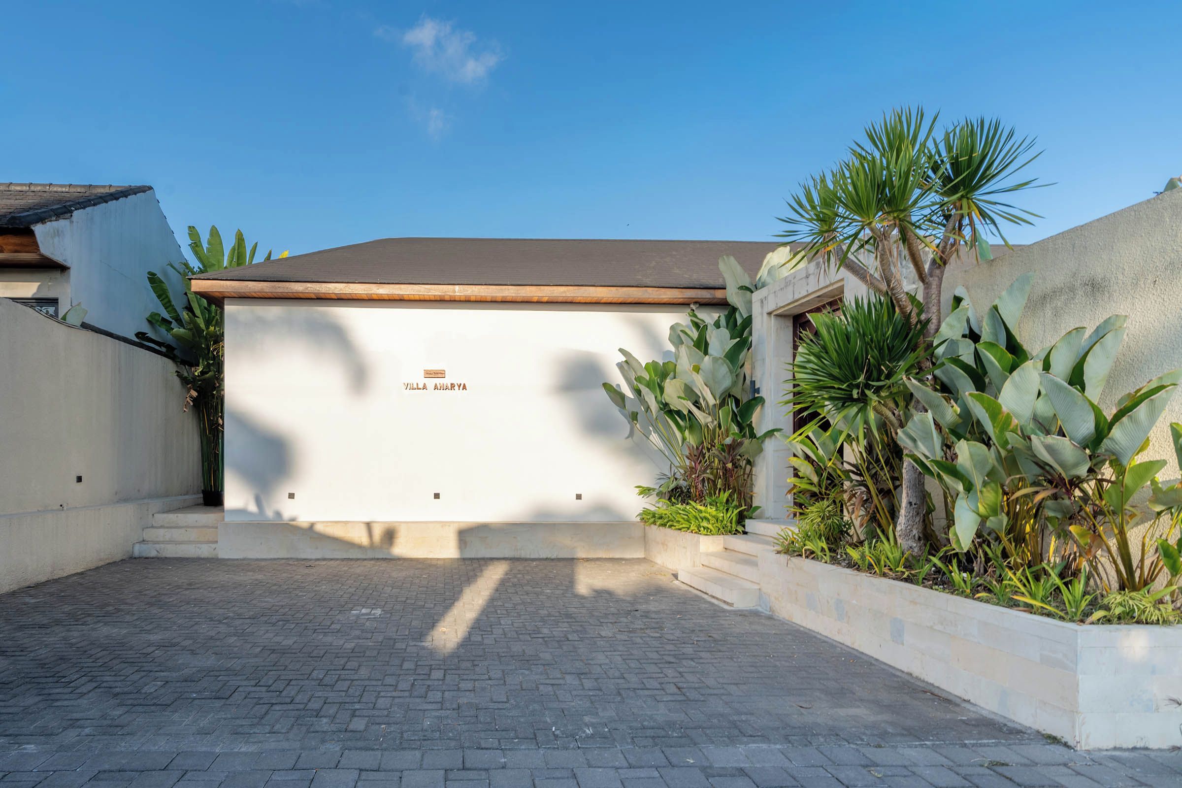 A villa with a white facade, a flat roof, and a sign reading 'Villa Aharya'.