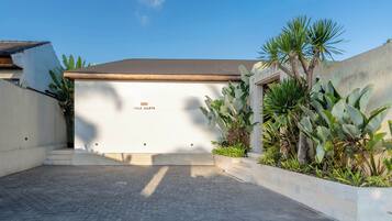 A villa with a white facade, a flat roof, and a sign reading 'Villa Aharya'.