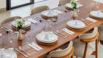 A long dining table set for a meal with multiple chairs, glassware, and white plates.