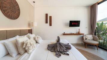 A hotel room with a large bed, a TV mounted on the wall, a small side table, and a view of the outdoors.