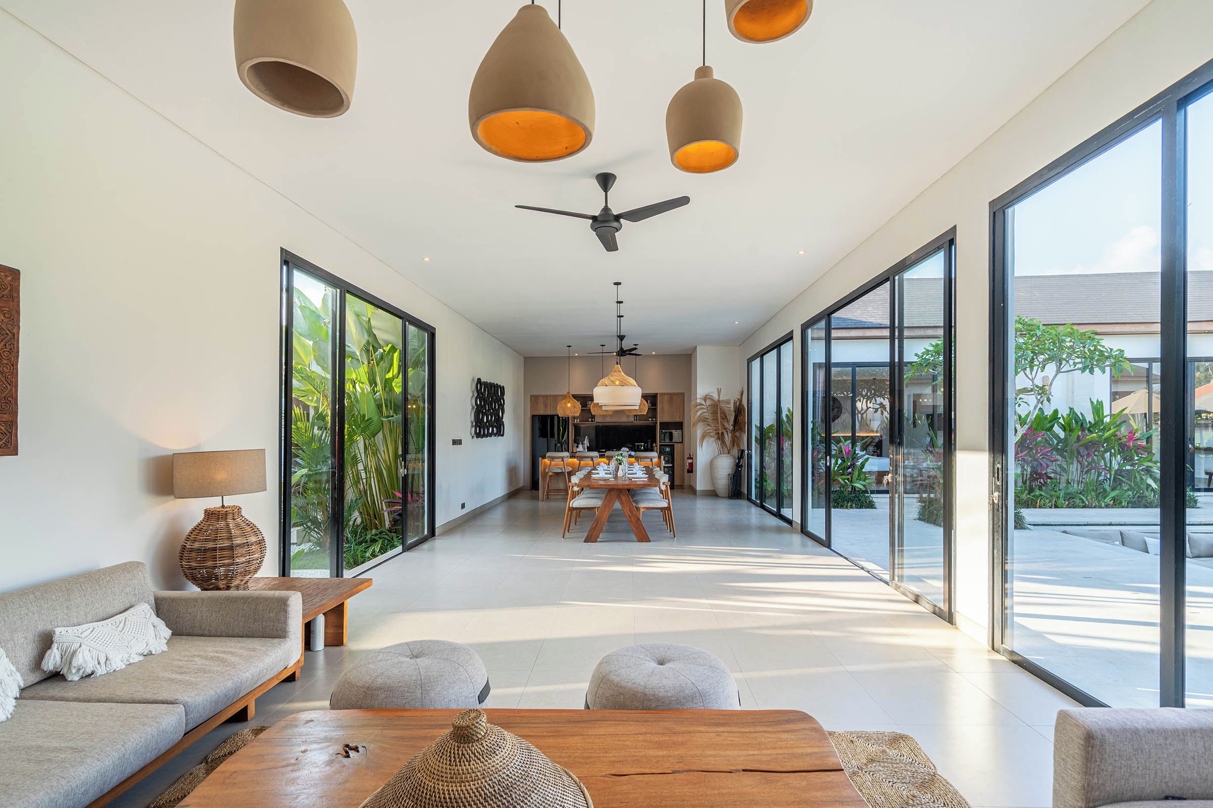 A modern interior with a dining area, sofas, and large windows.