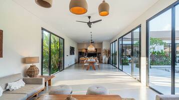 A modern interior with a dining area, sofas, and large windows.