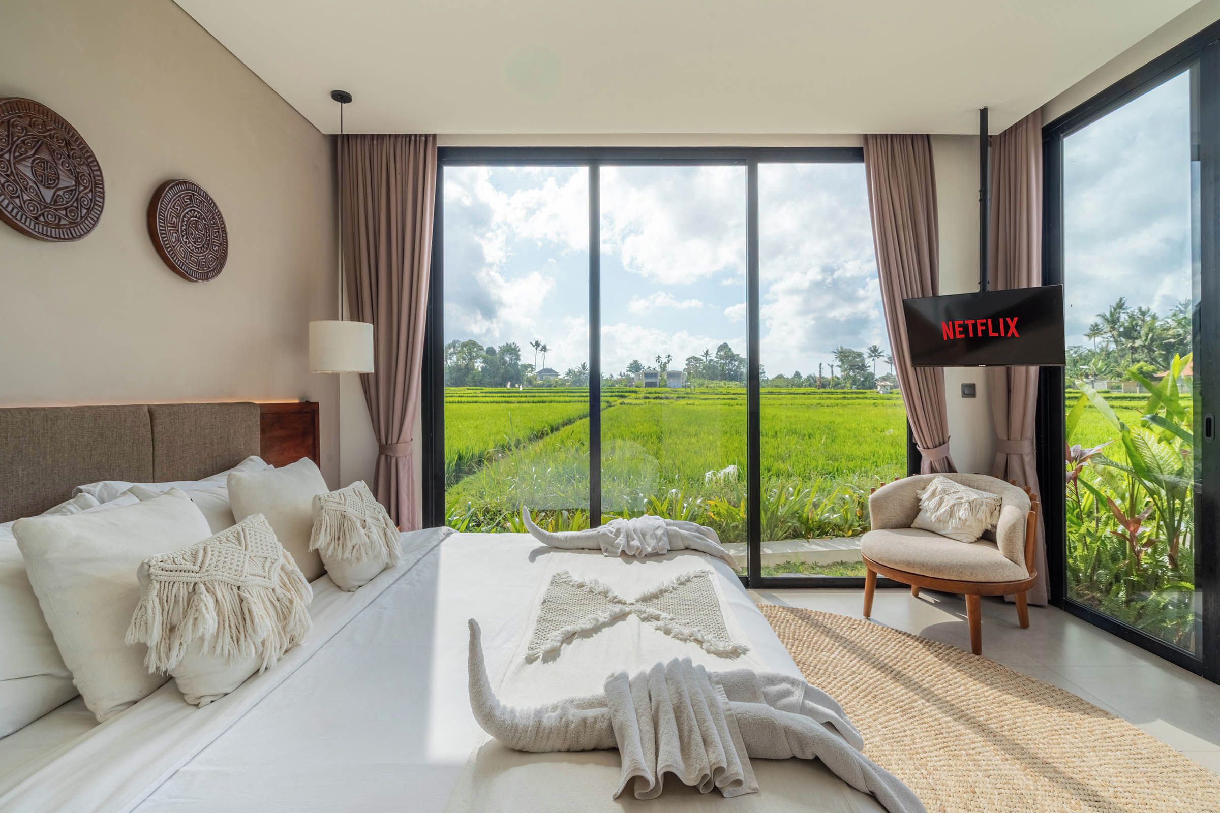 Ein modernes Schlafzimmer mit einem großen Bett, einem Fernseher und Blick auf ein grünes Feld.