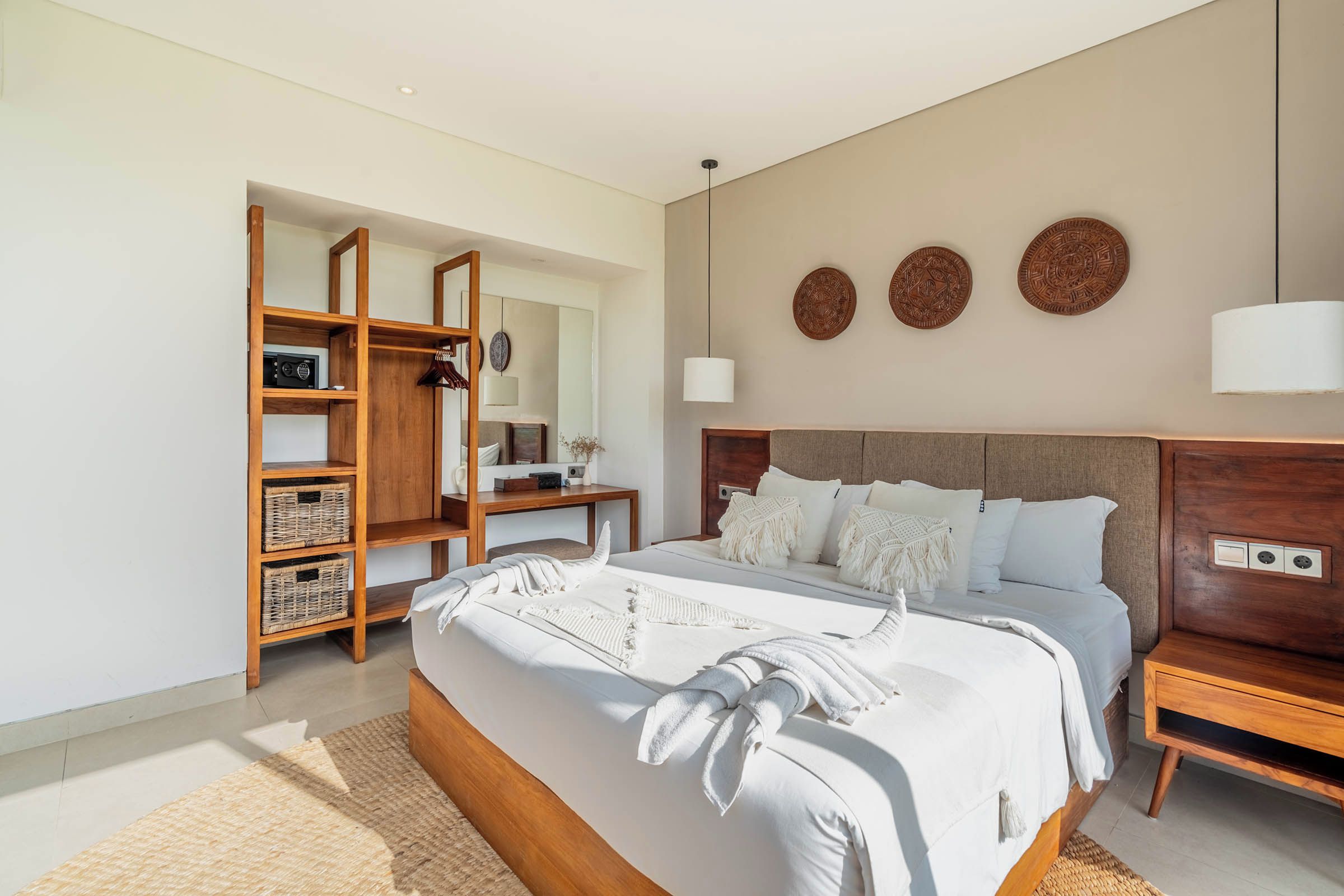 A modern bedroom with a large bed, wooden shelving, a bedside table, and a nightstand.