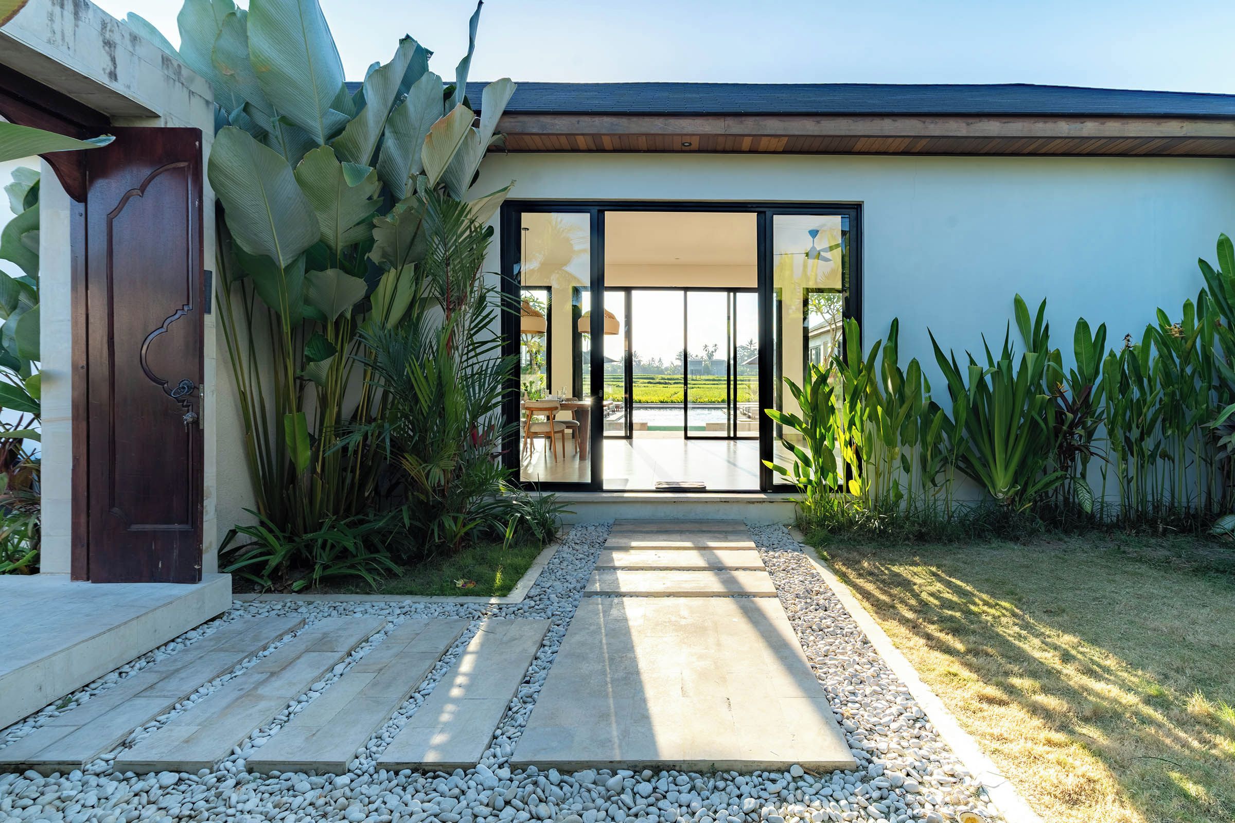 Ein modernes Haus mit einer großen Glasdoor, die auf eine Terrasse mit Blick auf eine grüne Landschaft führt.