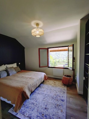 A bedroom with a bed, a window with a view, a radiator, and a hanging light fixture. - Welcome to Skimoon! Our family chalet with panoramic view of Haut Verdon valley (Villars-Colmars)